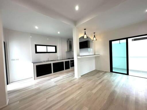 Modern kitchen with integrated living space, featuring sleek cabinetry and stylish lighting