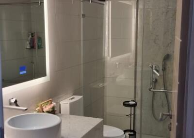 Modern bathroom with walk-in shower, sleek sink, and wall-mounted TV