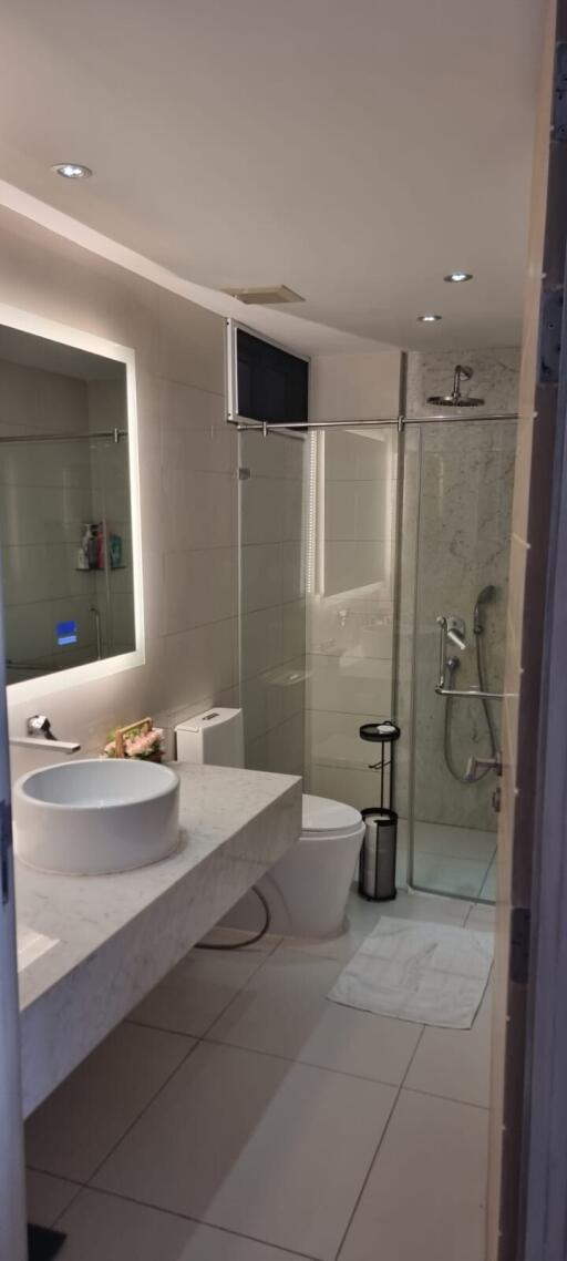 Modern bathroom with walk-in shower, sleek sink, and wall-mounted TV