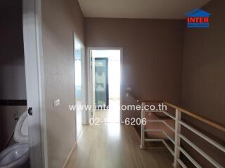 Spacious hallway leading to a bright room with wooden flooring and brown walls