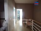 Spacious hallway leading to a bright room with wooden flooring and brown walls