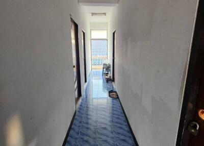 Narrow hallway with blue-tiled floor leading to a window