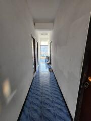 Narrow hallway with blue-tiled floor leading to a window