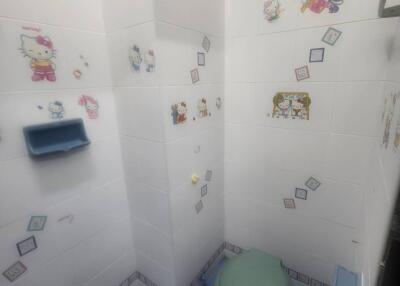 Bright children themed bathroom with tiled walls and cartoon stickers