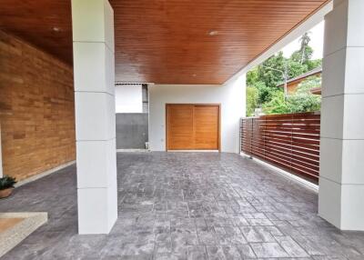 Covered patio area of a residential home showing modern design with a wooden ceiling and tiled flooring