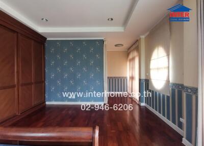 Spacious bedroom with wooden floor and elegant blue wallpaper