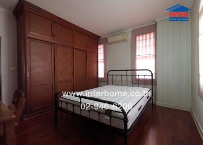 Spacious bedroom with large wooden wardrobe and air conditioning