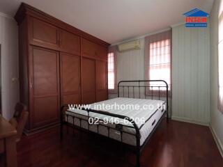 Spacious bedroom with large wooden wardrobe and air conditioning