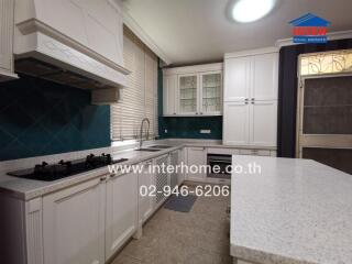 Modern kitchen with white cabinetry and teal backsplash in a home