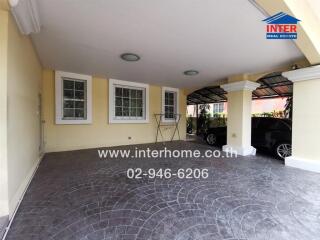 Covered parking area with patterned driveway and modern house exterior