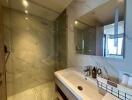 Modern bathroom with marble tiles and clear glass shower