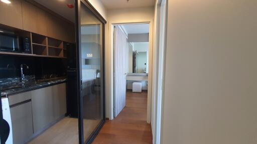 Modern apartment interior showing the kitchen leading into a bedroom with an open bathroom door