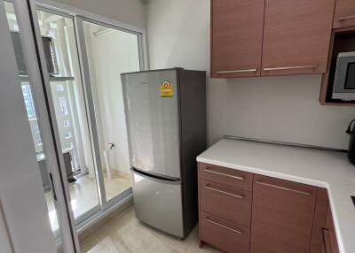 Compact modern kitchen with wooden cabinets and stainless steel refrigerator