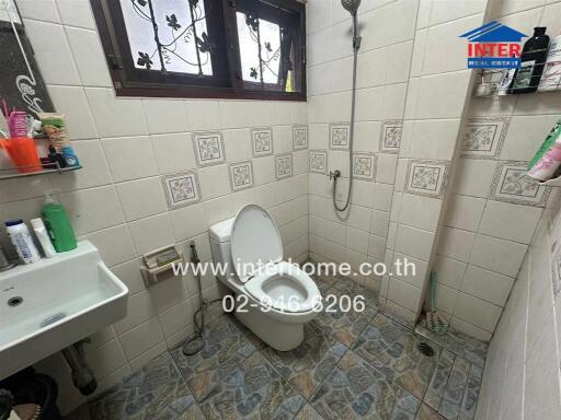 Bathroom with toilet and sink in a tiled room