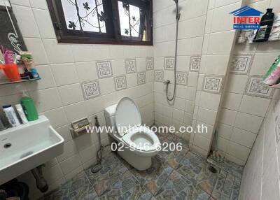 Bathroom with toilet and sink in a tiled room