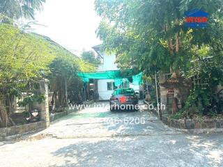 Suburban house front yard with parked car and lush greenery