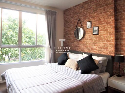 Stylish modern bedroom with a large window and an exposed brick wall