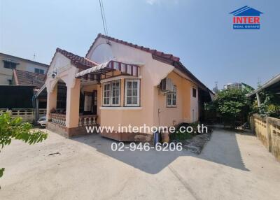 Exterior view of a charming single-story house with a tiled roof and a small front porch, ideal for property listings