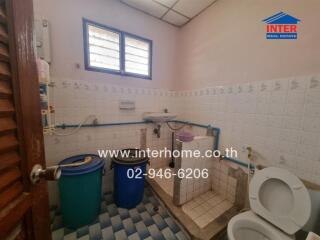 Compact bathroom with two windows, blue tiles, and basic fixtures