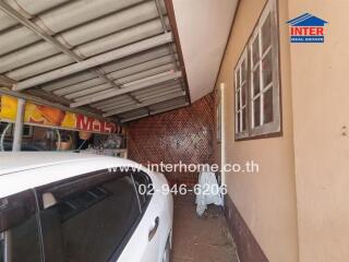 Covered parking garage with a white car and storage space