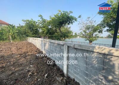 Land plot near water with boundary wall and mature trees