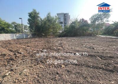 Empty residential plot with soil preparation in progress, nearby urban buildings