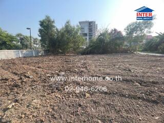 Empty residential plot with soil preparation in progress, nearby urban buildings