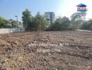 Empty residential plot with soil preparation in progress, nearby urban buildings