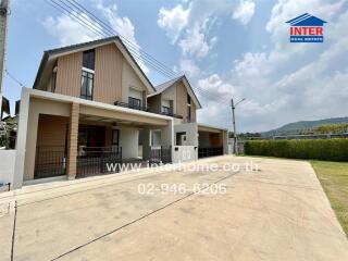 Modern two-story house with wooden and concrete facade, spacious driveway, and clear skies