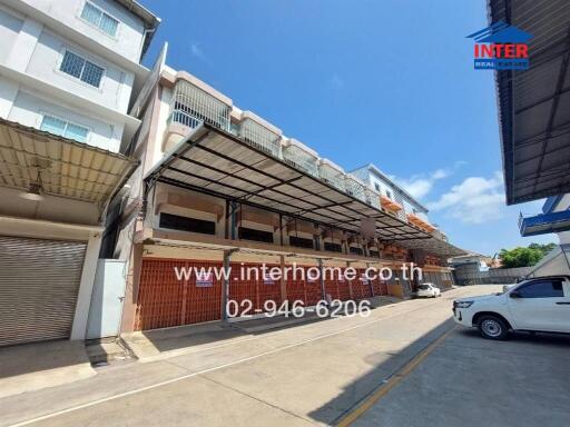 Exterior view of a row of terraced commercial properties with awnings and parking