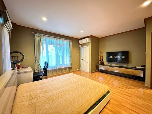 Modern bedroom with wooden floor, large bed, TV, and workstation