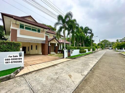 Front view of a suburban house with for sale sign and palm trees