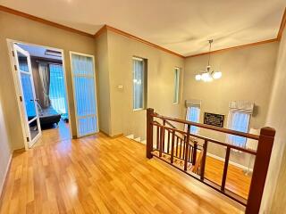 Spacious hallway with wooden flooring and staircase leading to upper or lower levels.