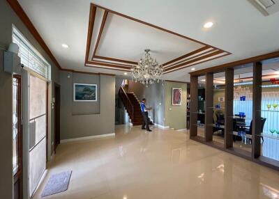 Spacious and well-lit living area with elegant chandelier and staircase