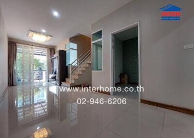 Spacious living room with glossy tiled flooring, staircase, and access to other areas