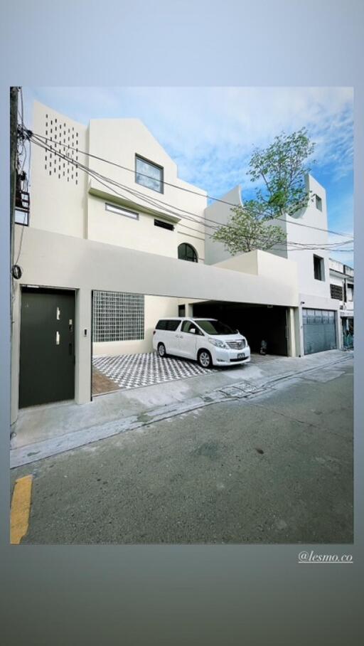 Modern two-story residential building with carport and SUV
