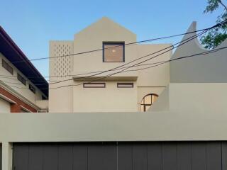 Modern two-story residential building with a flat roof and geometric design, evening view