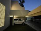 Evening view of a modern home's exterior with a car parked under a carport
