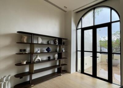 Spacious living room with large arched window and modern shelving unit