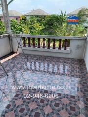 Spacious tiled balcony with decorative railing overlooking neighboring houses