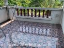 Spacious tiled balcony with decorative railing overlooking neighboring houses