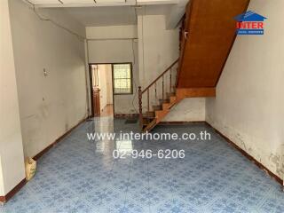 Interior view of a spacious living area with staircase and tiled flooring