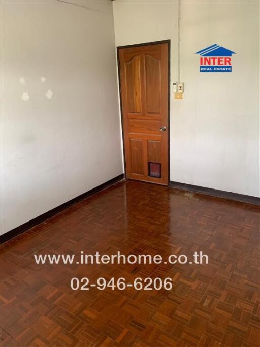 Empty bedroom with wooden parquet flooring and a wooden door
