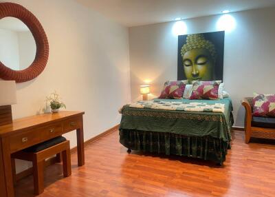 Spacious bedroom with Buddha artwork and hardwood flooring