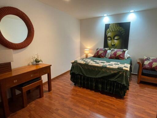 Elegant bedroom with Buddha wall art and hardwood flooring