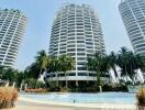 Luxurious high-rise residential buildings with a large swimming pool surrounded by palm trees