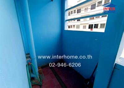 Narrow exterior passageway of a residential building with bright blue walls