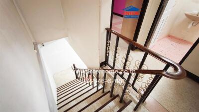 Interior view of a staircase with white walls and wooden handrail