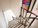 Interior view of a staircase with white walls and wooden handrail