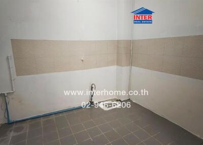 Empty kitchen space with wall tiles and plumbing fixtures